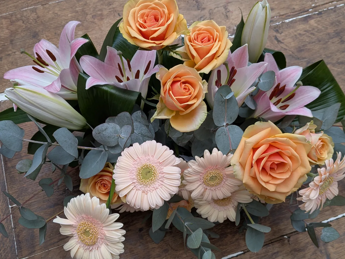 Détail de roses pêche, lys roses, gerberas et eucalyptus